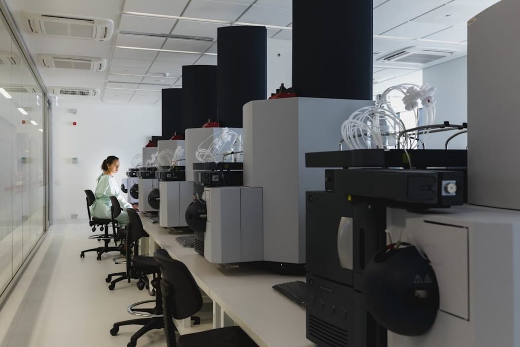 A young female scientist sits alone at a long laboratory bench.